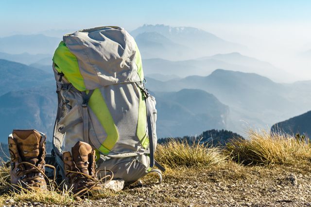 A backpack and boots on top of the mountain.