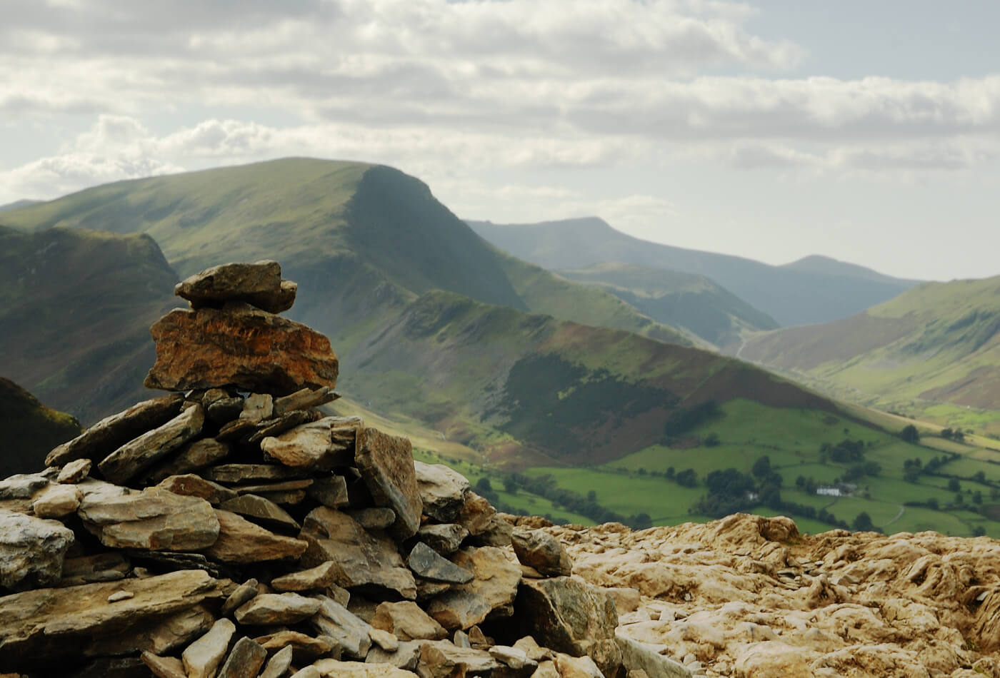 A collection of stones at the top of Catbells with a backdrop of the Lake District