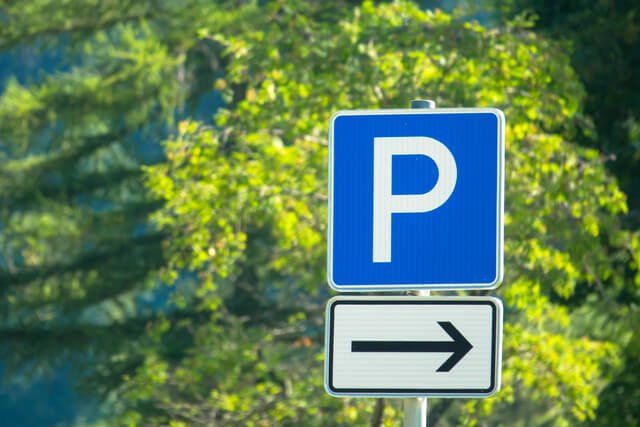 A parking sign with trees in the background