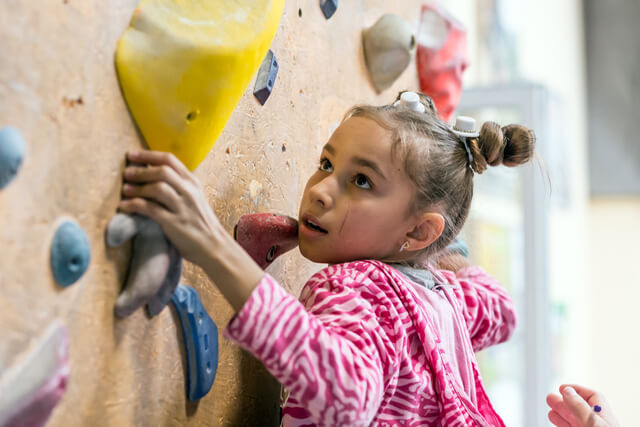 A young girl climbing an indoor climbing wall
