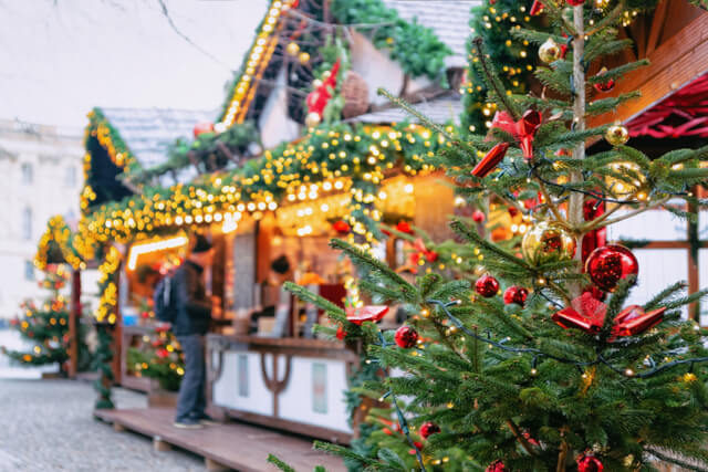 A shot of a decorated christmas tree with a market stall in the background 