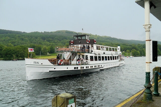 A white boat on the water nearing the dock at Lakeside Pier