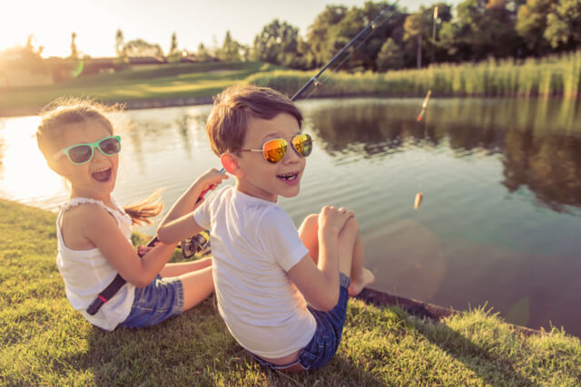 Two young children fishing in a lake as the sunsets
