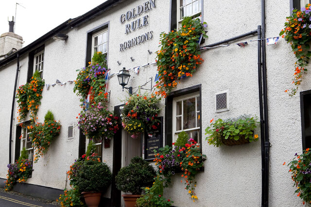 The whitewashed exterior of the Golden Rule pub decorated in vibrant flowers