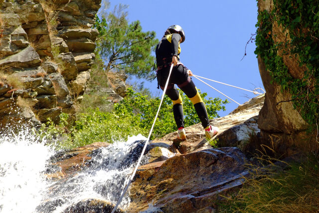 Woman abseiling with ropes down a rockface
