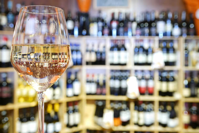 A glass of wine on the counter in a stocked wine shop