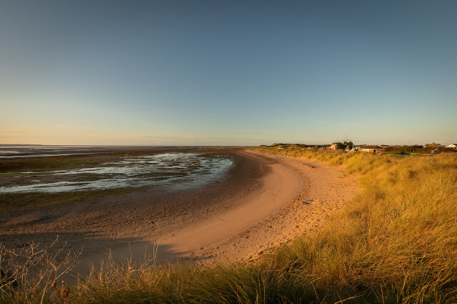 A view across the sand and sea at Haverigg Beach from the grassy dunes sitting behind