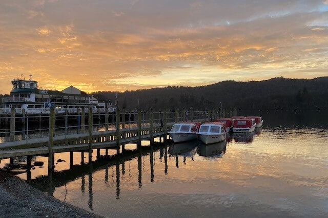 Boats and a landing pier on Lake Windermere at sunset