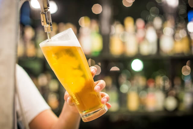 A hand pulling a pint of lager in a pub