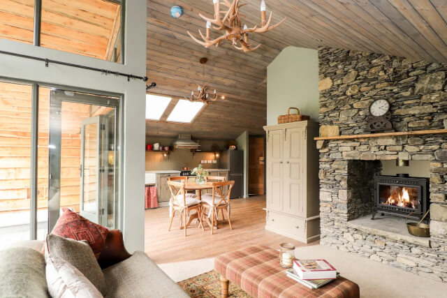 An interior shot of The Hares Shack showing a wooden ceiling stone fireplace and rustic furniture