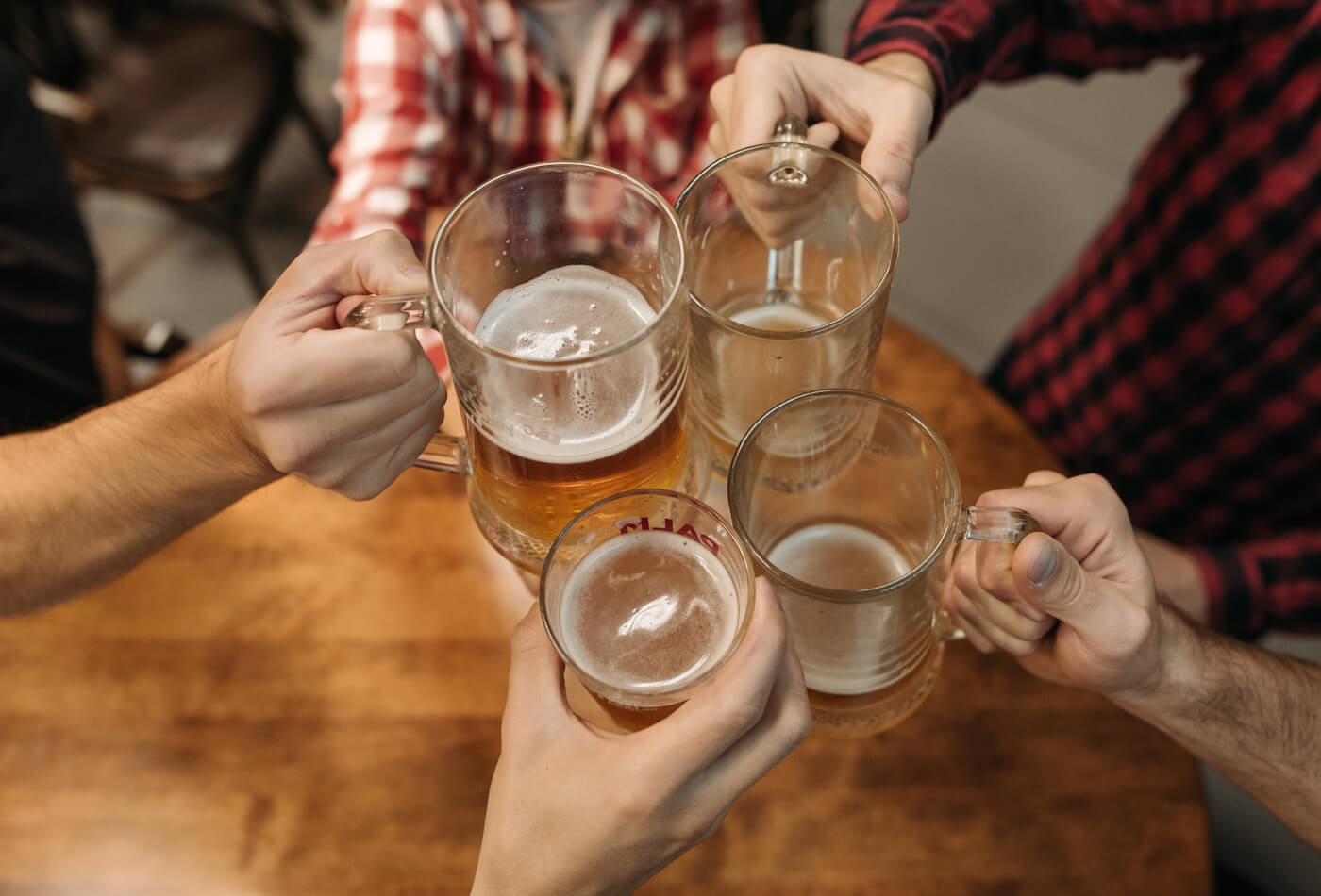 Four hands holding pint glassses cheersing