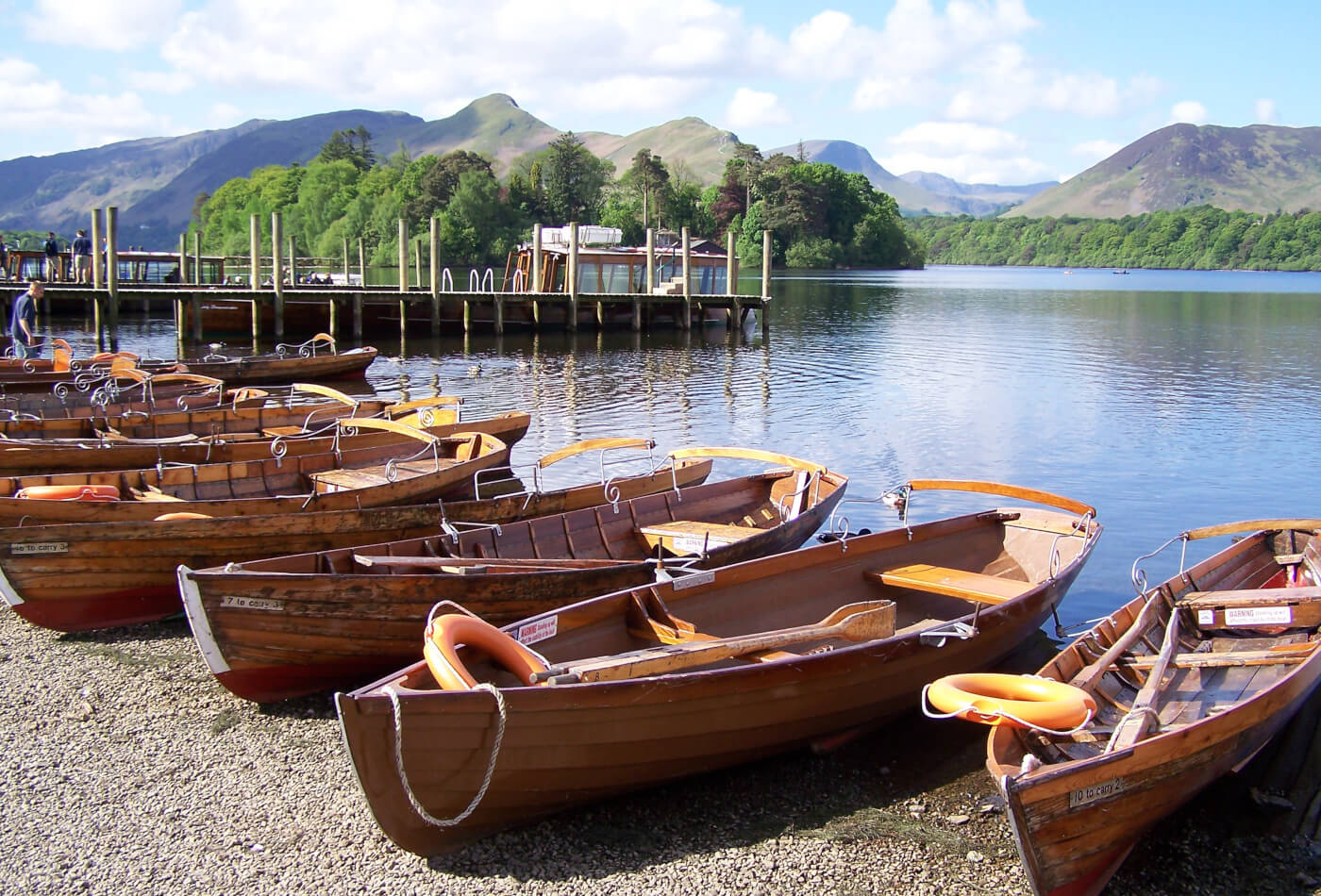 A row of wooden rowing boats on the shore of Derwentwater