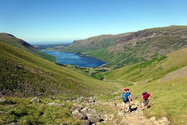 People hiking on Scafell Pike surrounded by green mountains